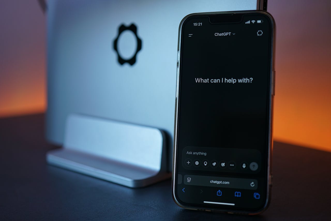 Close-up of a smartphone showing a chat interface with a laptop in the background.